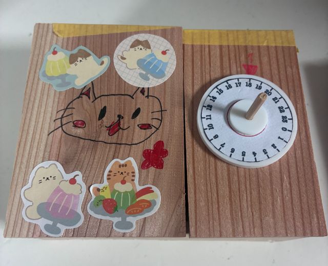 大きなねこの顔を描き、ねことスイーツのシールで飾った暗号キーボックス
