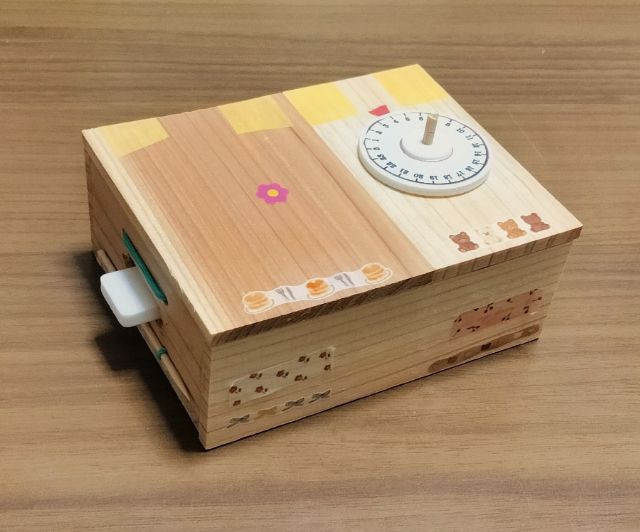 木目を生かし、花やくま、食べ物などの小さなシールで飾った暗号キーボックス