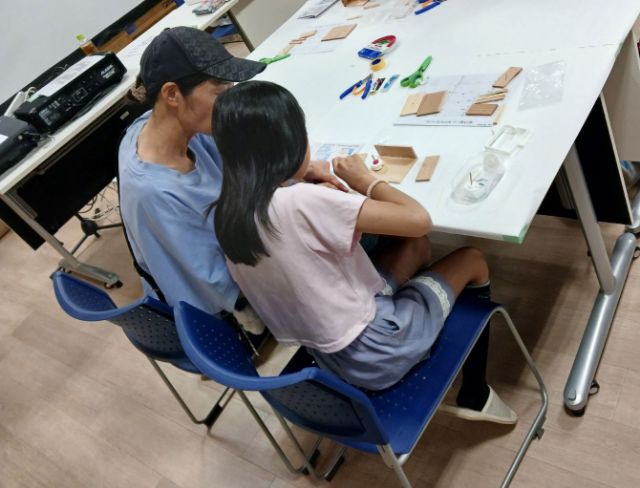 親子で木の板とダイヤルの部品を確認しながら暗号キーボックスを製作している様子
