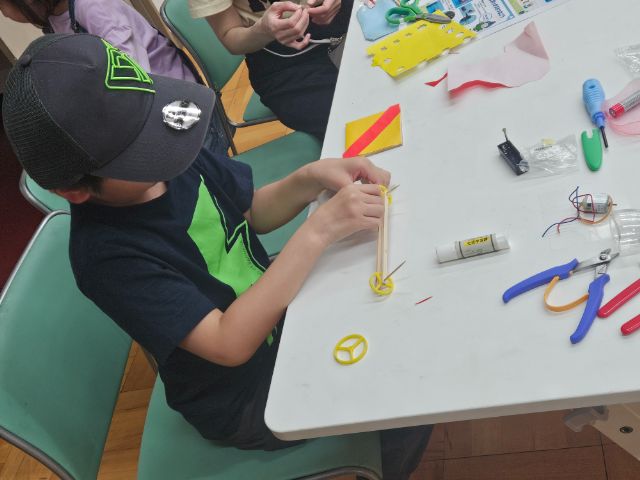 三輪モーターカーの部品を取り付けながら工作する子どもの様子