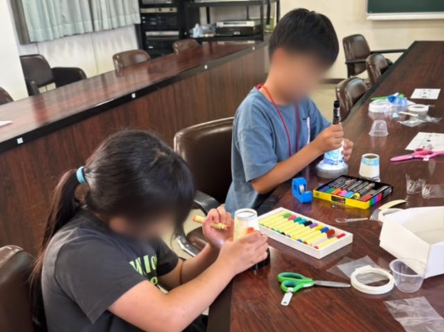 完成した万華鏡の紙コップにペンでデコレーションする子どもたち