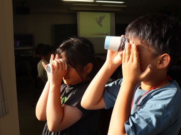 窓から差す自然光に万華鏡をかざして楽しむ子どもたち