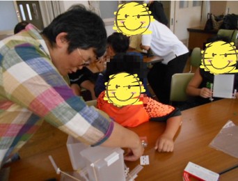 講師と一緒にごみ箱の部品の位置を確認する児童